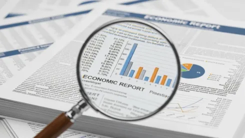 Uma lente de aumento dando destaque em gráficos financeiros em uma folha de papel